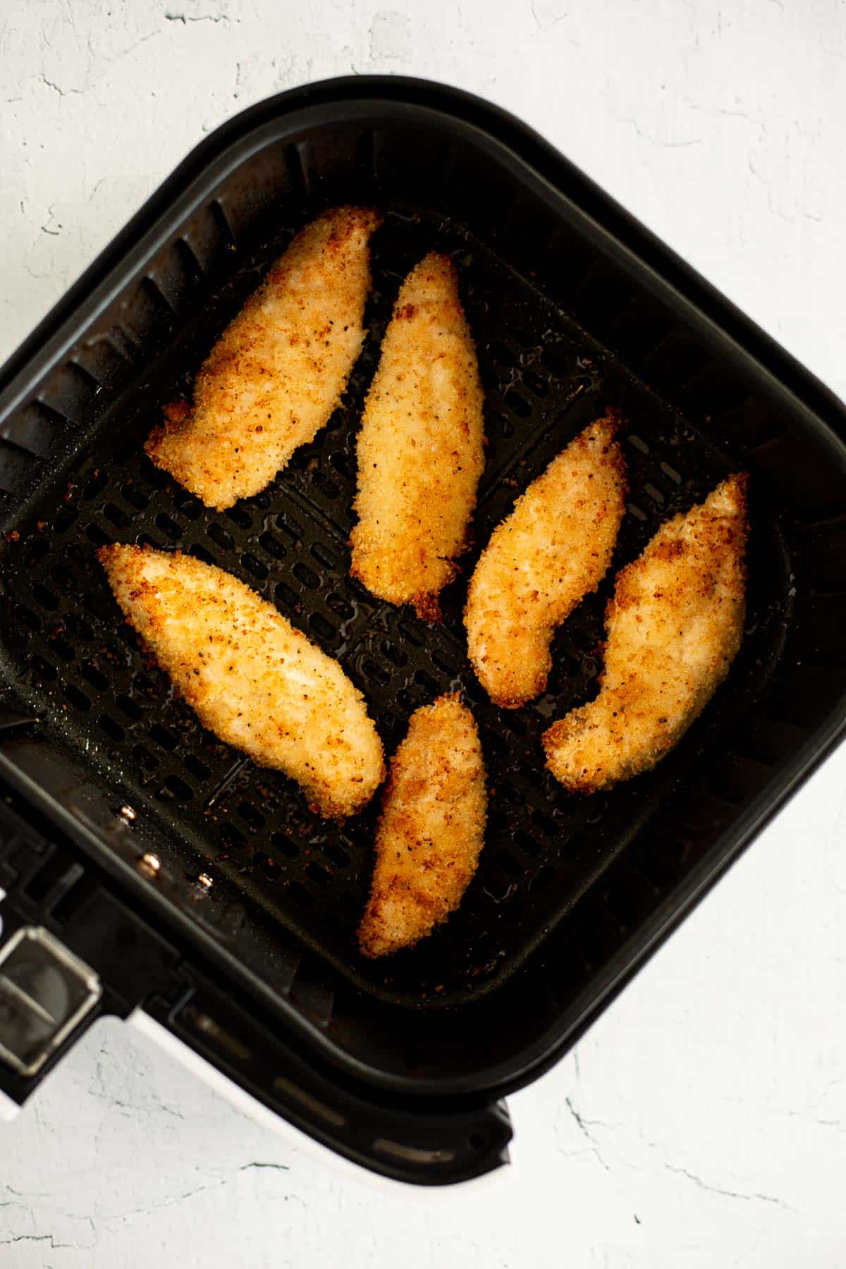 crispy, golden brown chicken tenders in air fryer basket.