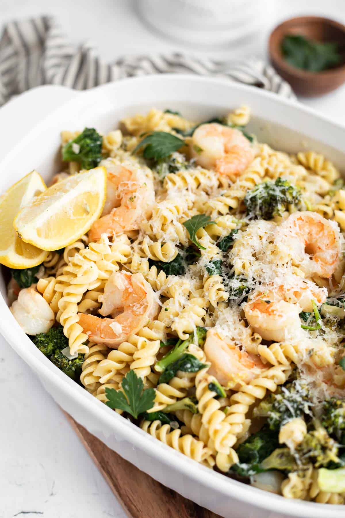 pasta with shrimp, broccoli, and lemon in a white serving dish.