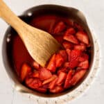homemade strawberry compote in a silver pot with a wooden spoon.