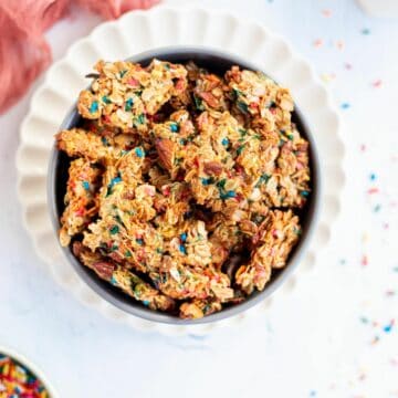 a bowl of birthday cake granola clusters on a white plate.