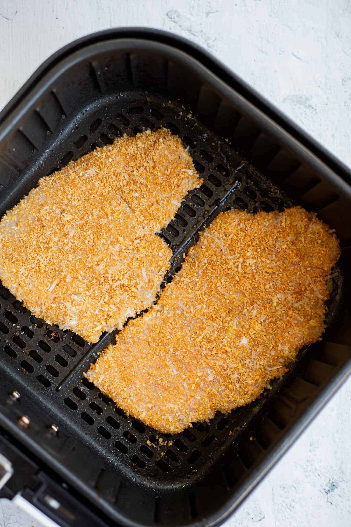 2 pieces of breaded chicken in the air fryer basket.