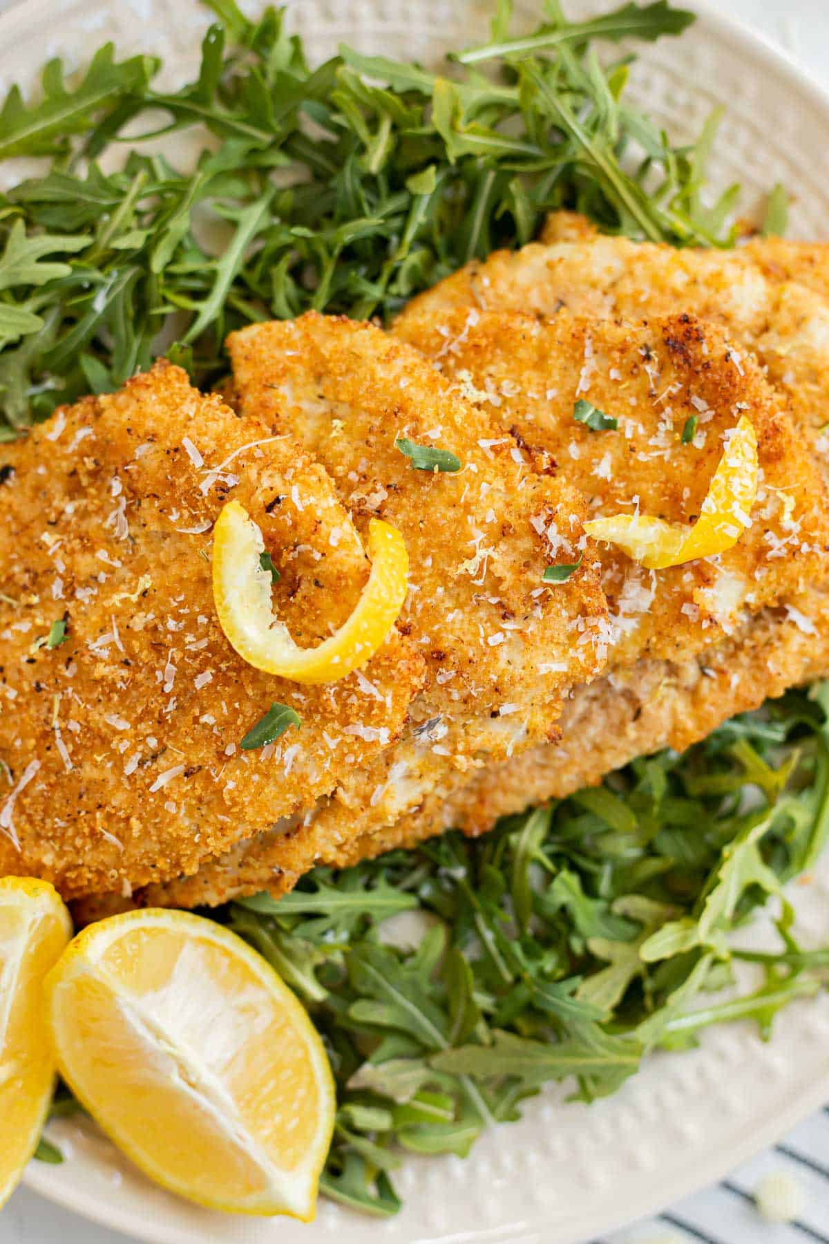 3 pieces of breaded chicken laid out on a bed of arugula.