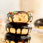 three baked banana donuts with a chocolate glaze stacked on a plate.