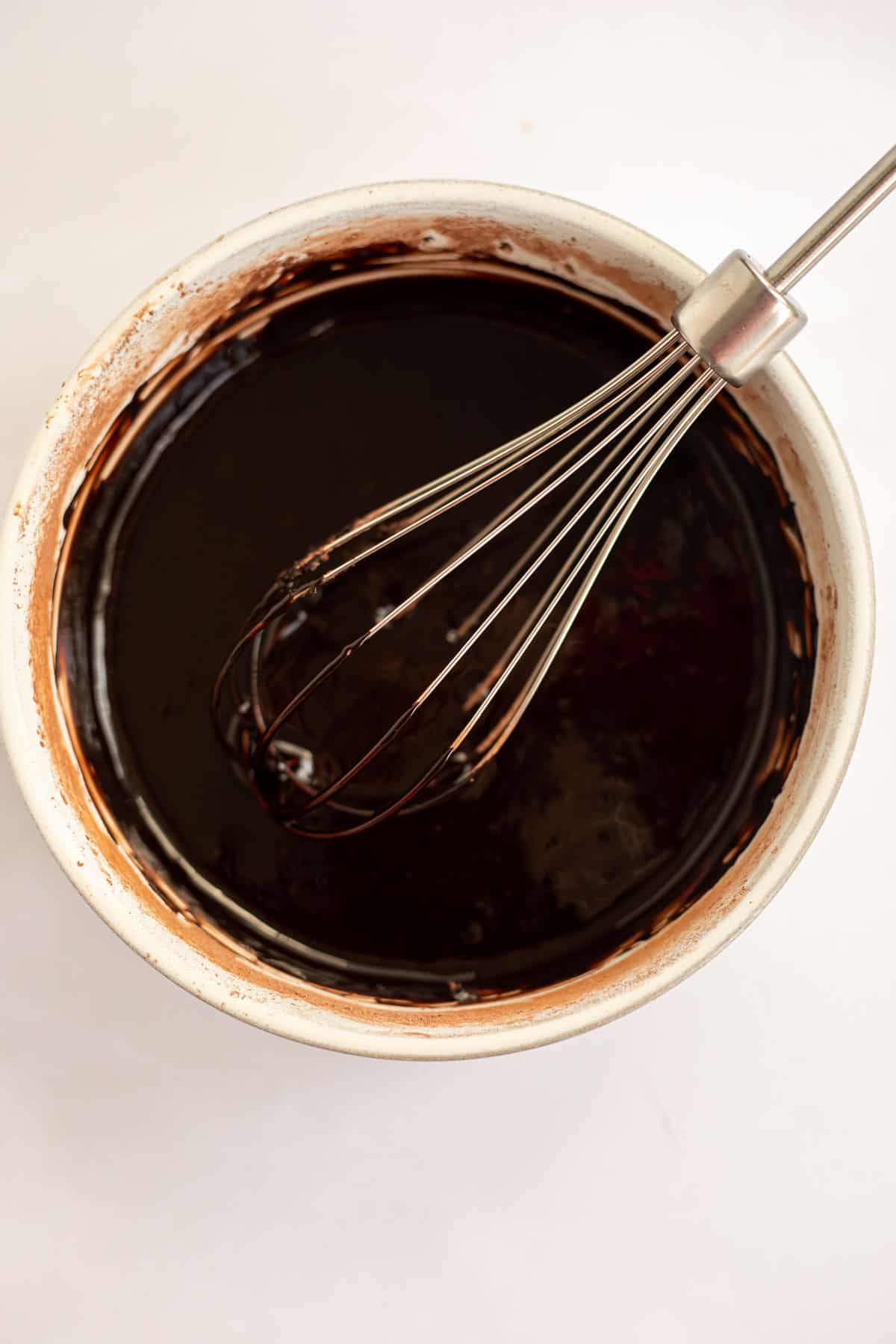 silky chocolate donut glaze whisked together in a white bowl.