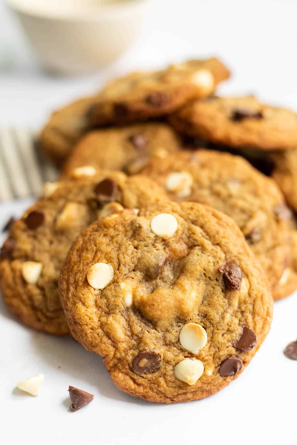 a pile of maple chocolate chip cookies with white chocolate chips on a white background.