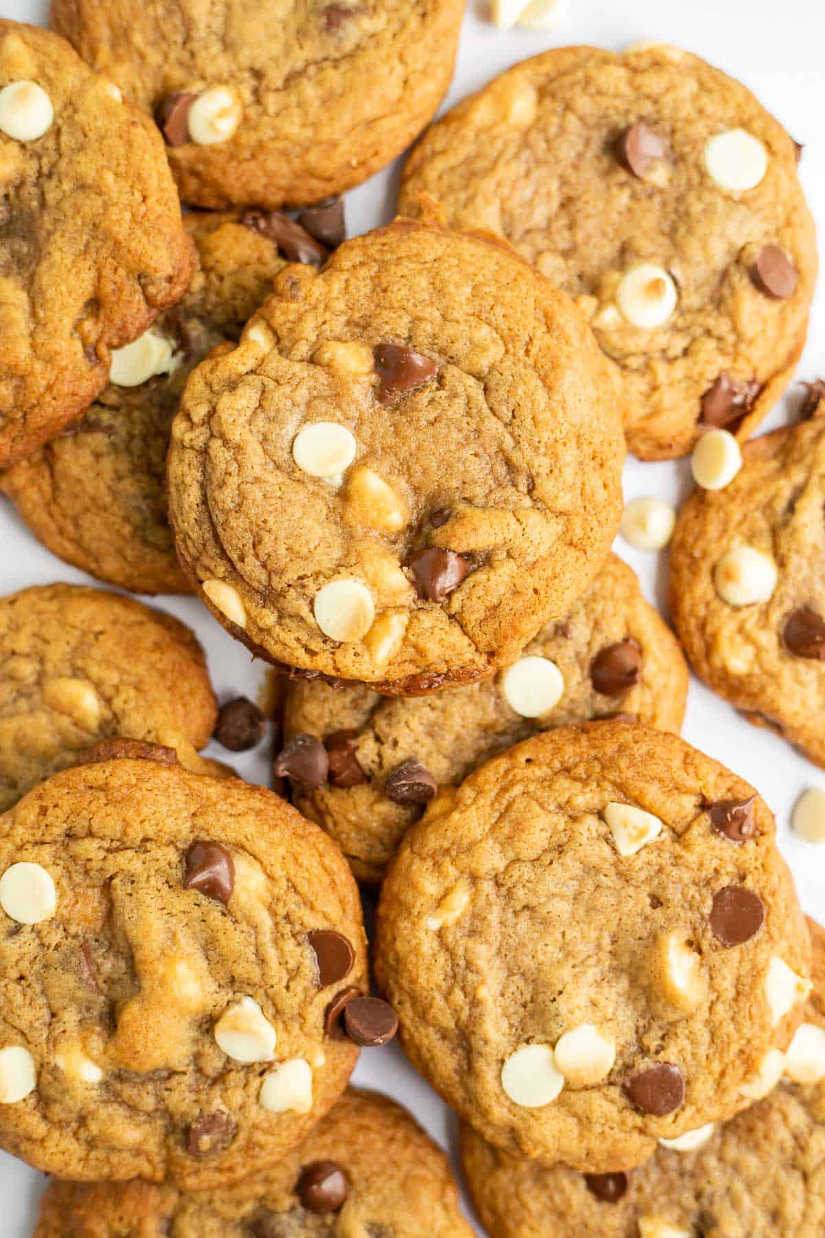 maple syrup chocolate chip cookies with white chocolate spread out on a white backdrop.