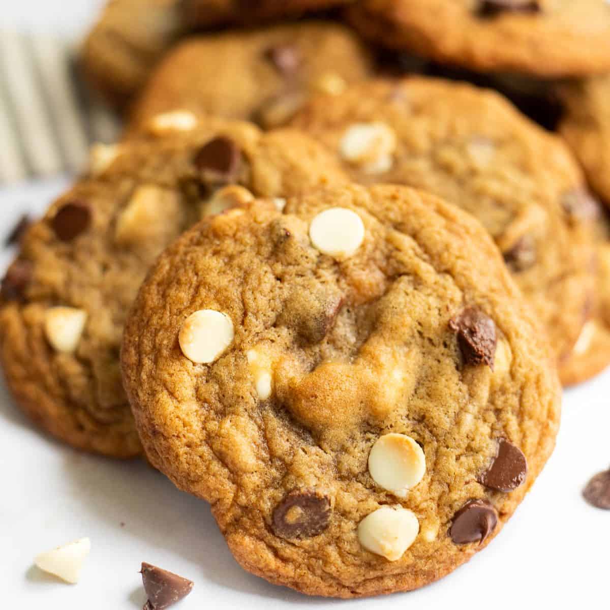 a pile of maple chocolate chip cookies with white chocolate on a white backdrop.