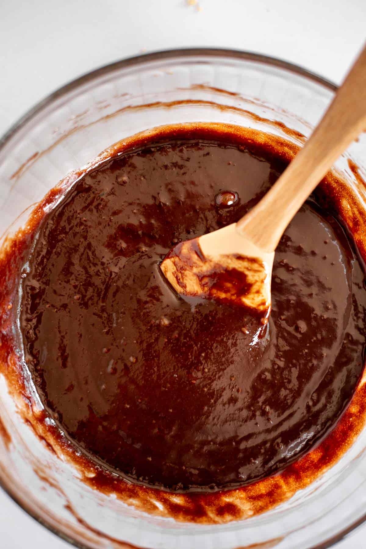 melted chocolate, butter, eggs, and sugar mixed together in a glass bowl with a spatula.