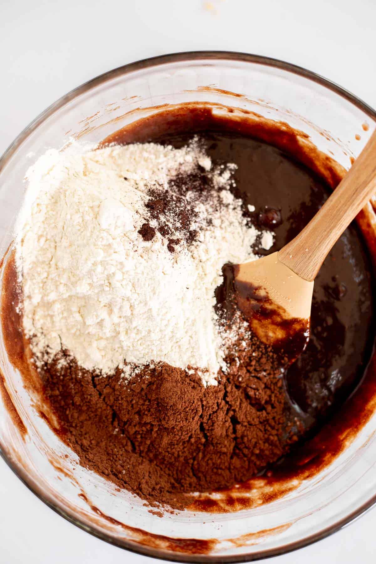 flour and cocoa mixing into melted chocolate mixture for brownies.