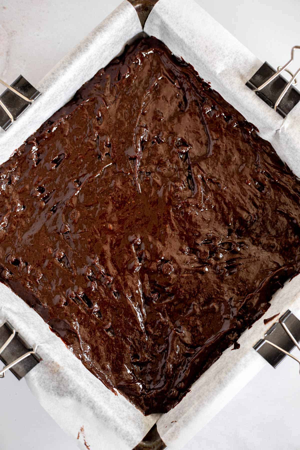 fudgy brownie batter in a baking pan lined with parchment paper.