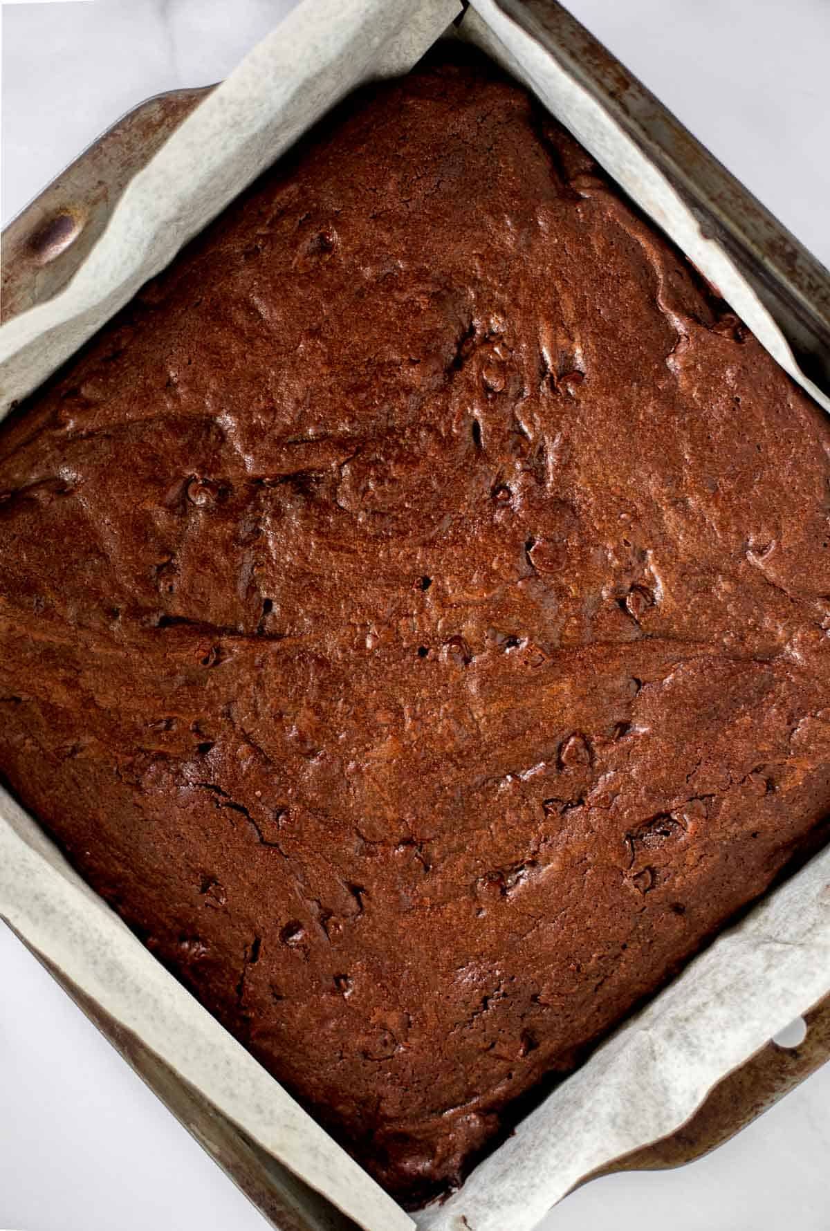 baked brownies in a pan lined with parchment paper.