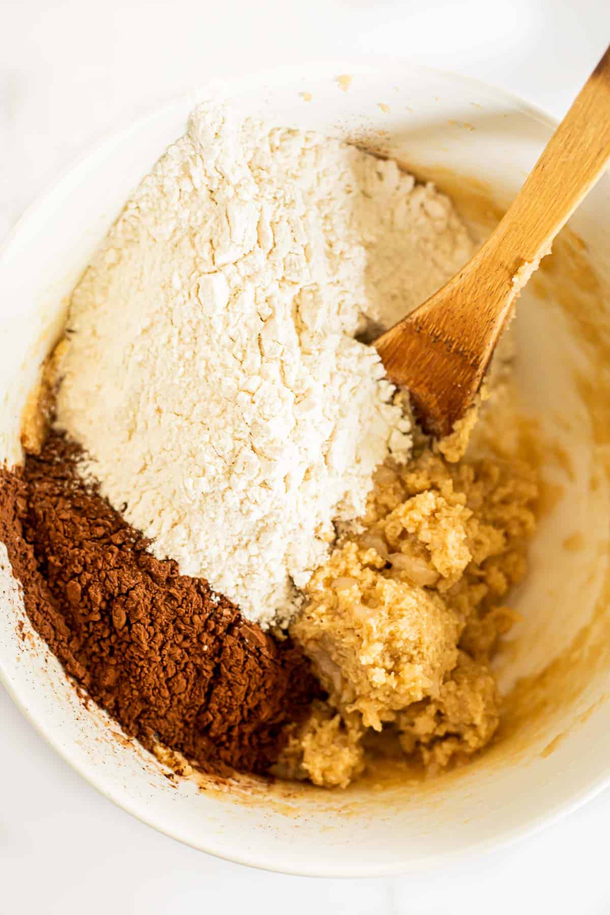 Flour, cocoa powder, and salt in a white bowl with creamed butter and sugar.