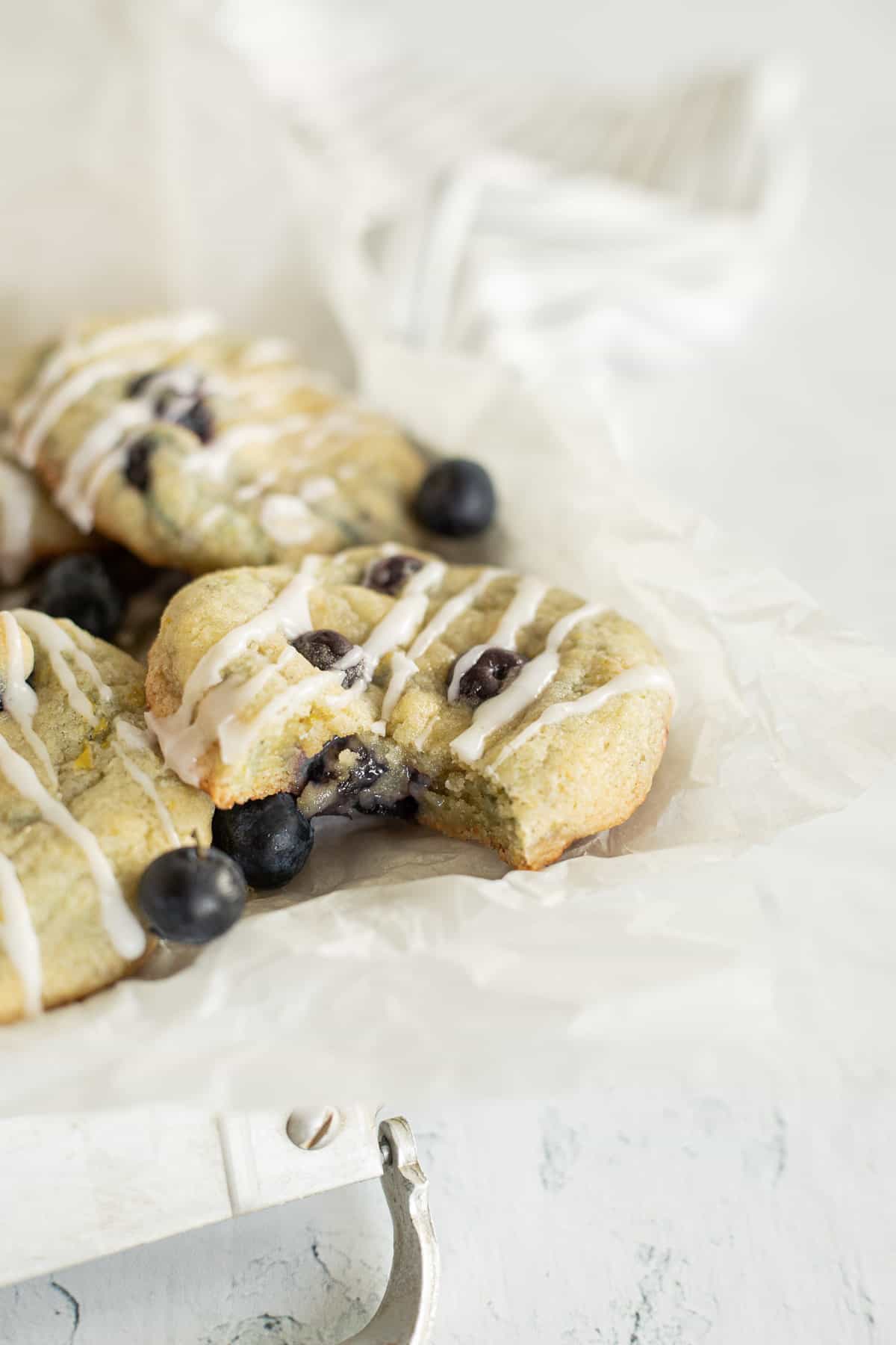 glazed blueberry lemon cookies on a parchment lined silver tray.