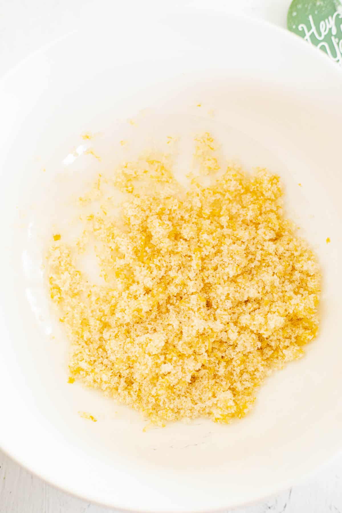 granulated sugar rubbed with lemon zest in a white bowl.