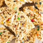 a pile of M&M rice krispie treats with white chocolate on parchment paper.