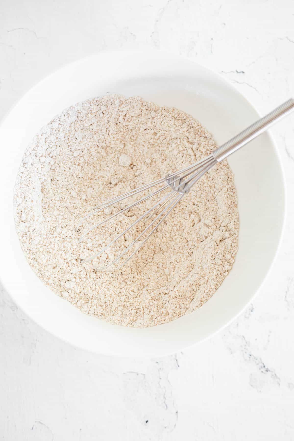 gluten free flour, baking soda, and salt whisked together in a white bowl.