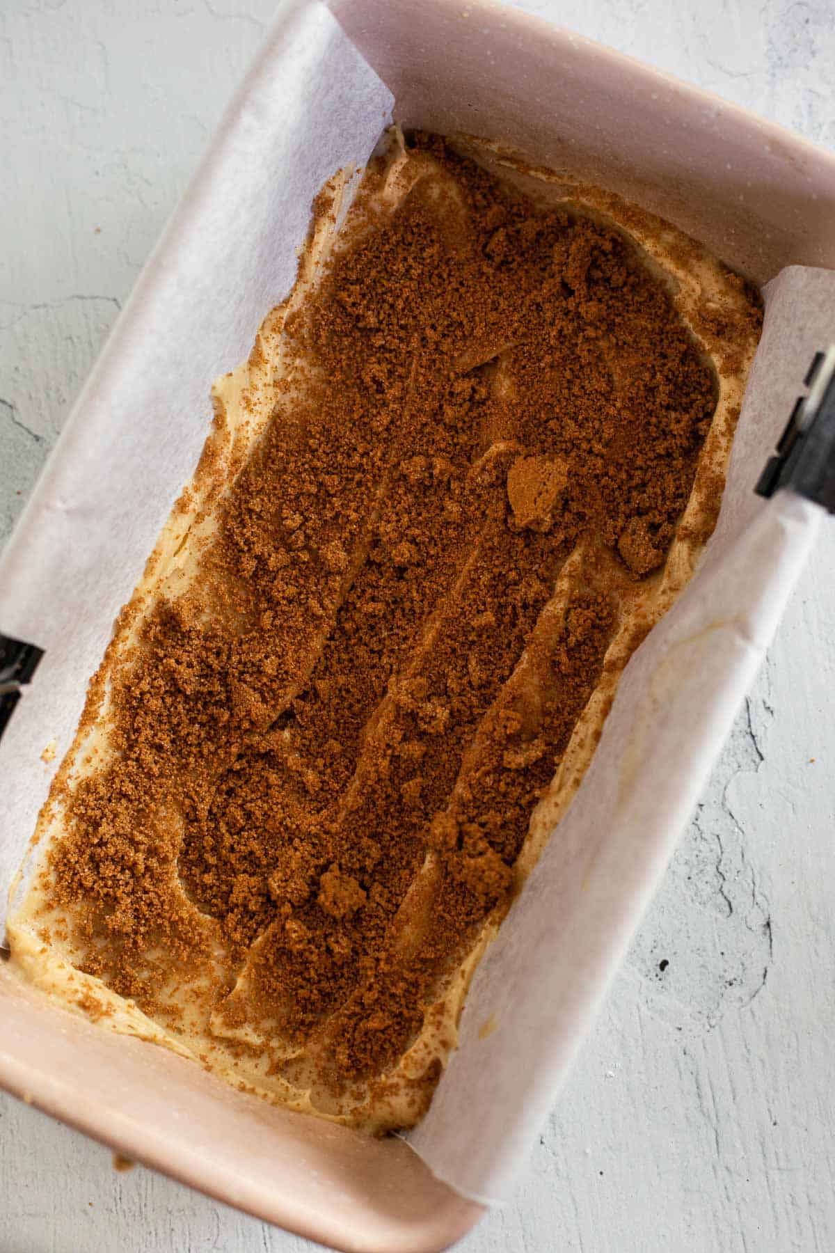 cake batter in a loaf pan topped with a sprinkle of cinnamon sugar.