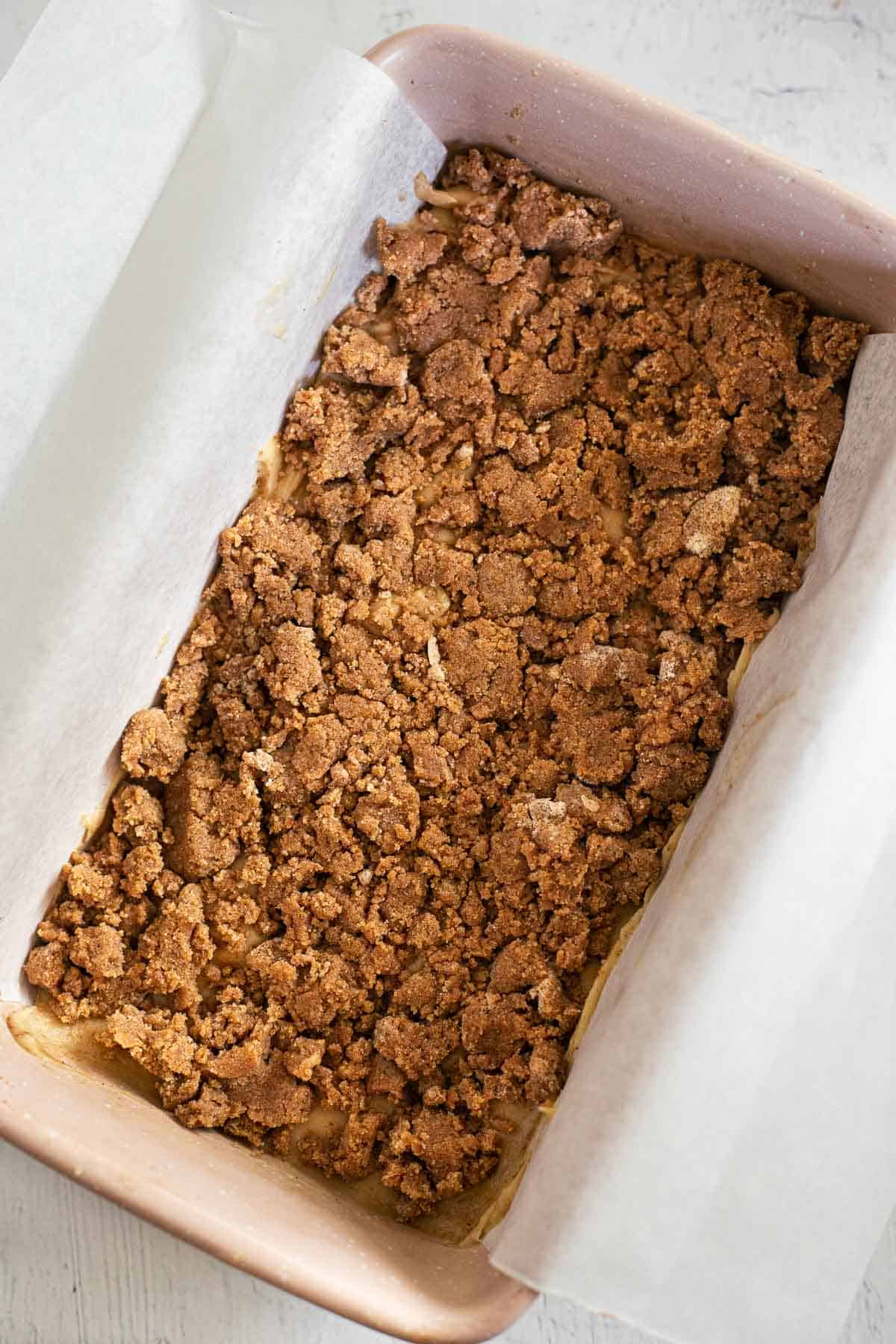 unbaked coffee cake in a pink loaf pan.
