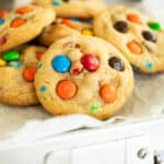 6 M&M cookies in a metal container lined with parchment paper.