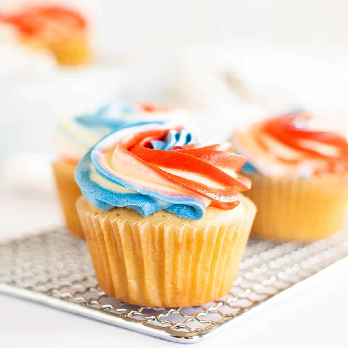 patriotic cupcakes on a metal rack on a white background.