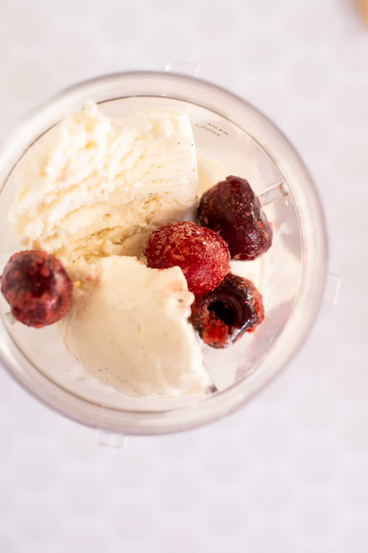 frozen cherries and vanilla ice cream in a blender cup.