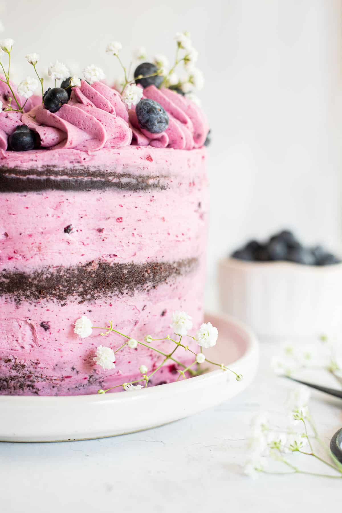 half of a chocolate blueberry cake with flowers and fresh blueberries.