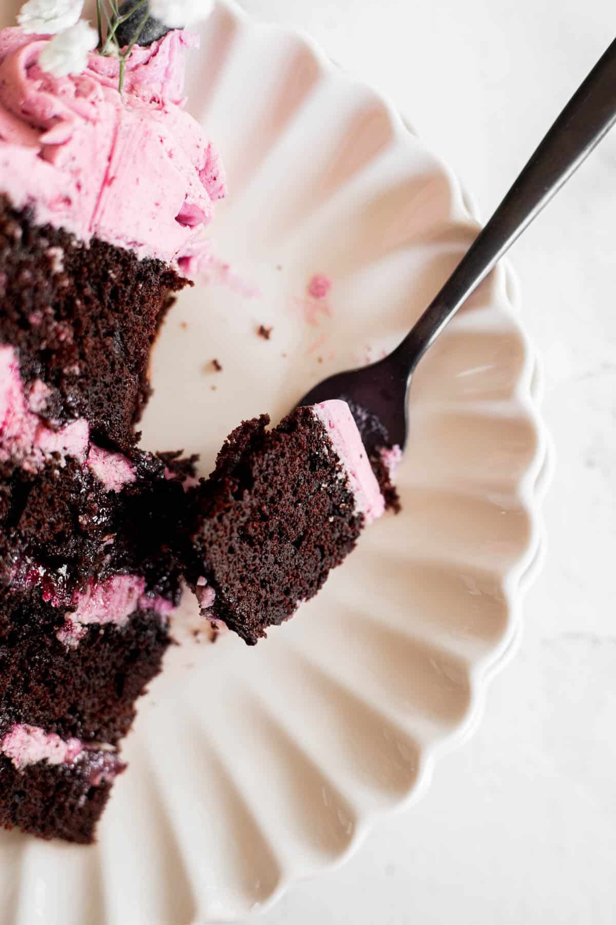a slice of chocolate cake with blueberry filling and icing on a white plate.