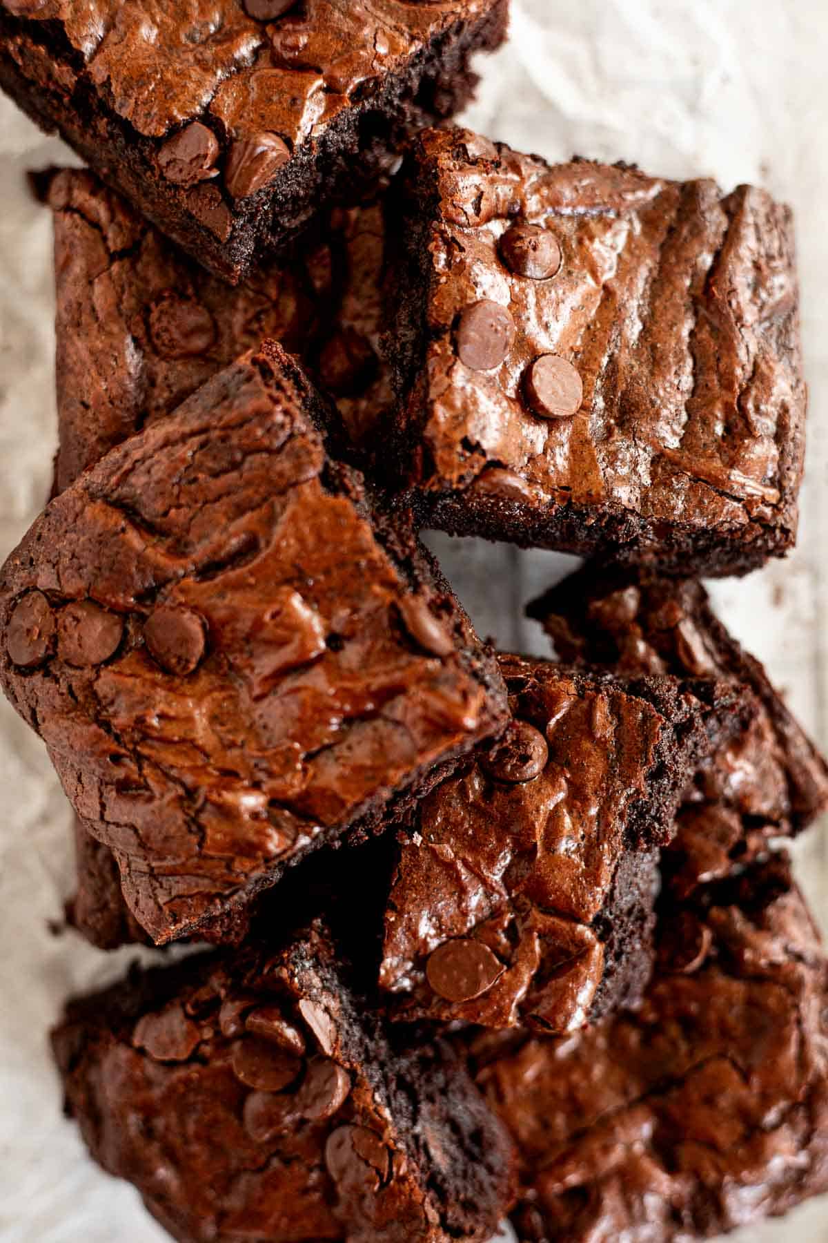 squares of small batch brownies piled on top of each other on parchment paper.