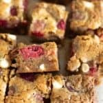 white chocolate raspberry blondies cut into squares on parchment paper.