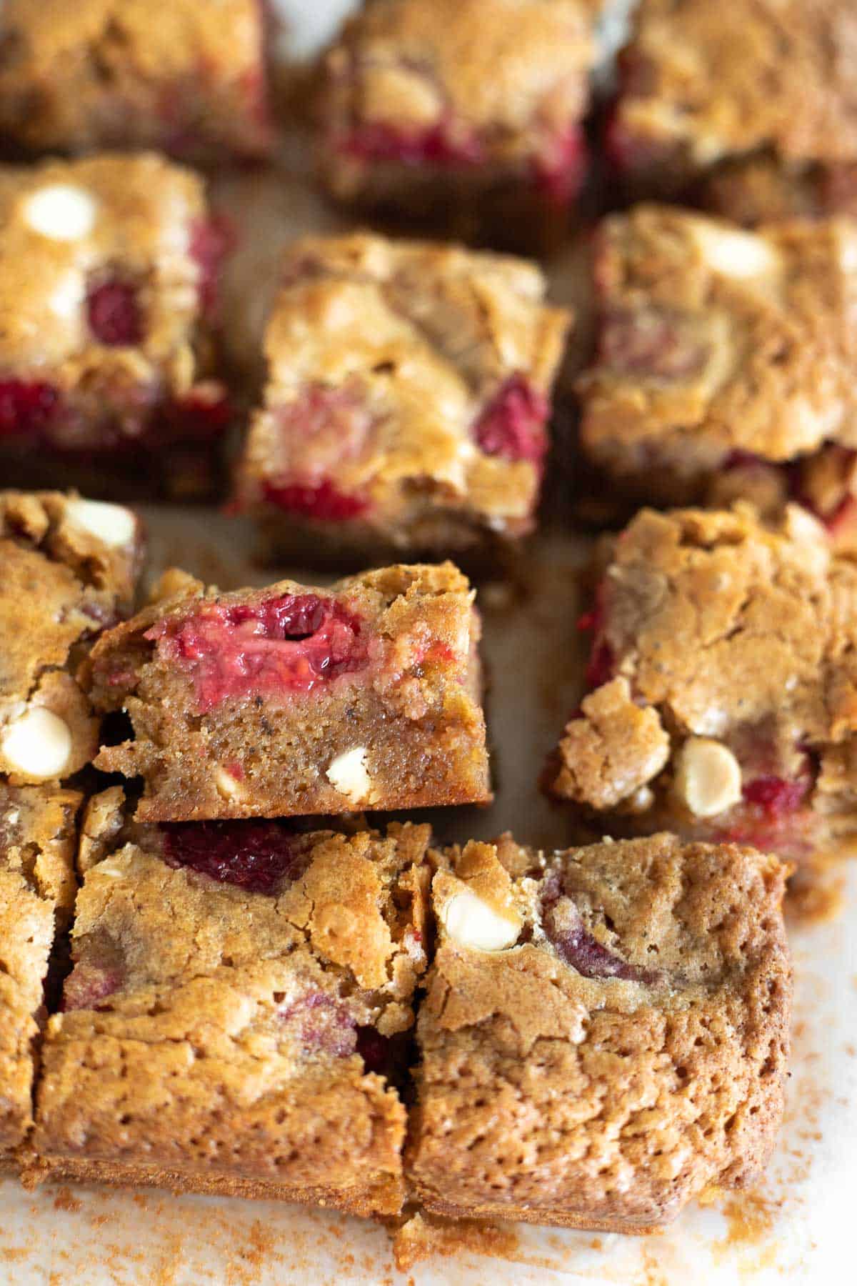 white chocolate raspberry blondies cut into squares on parchment paper.
