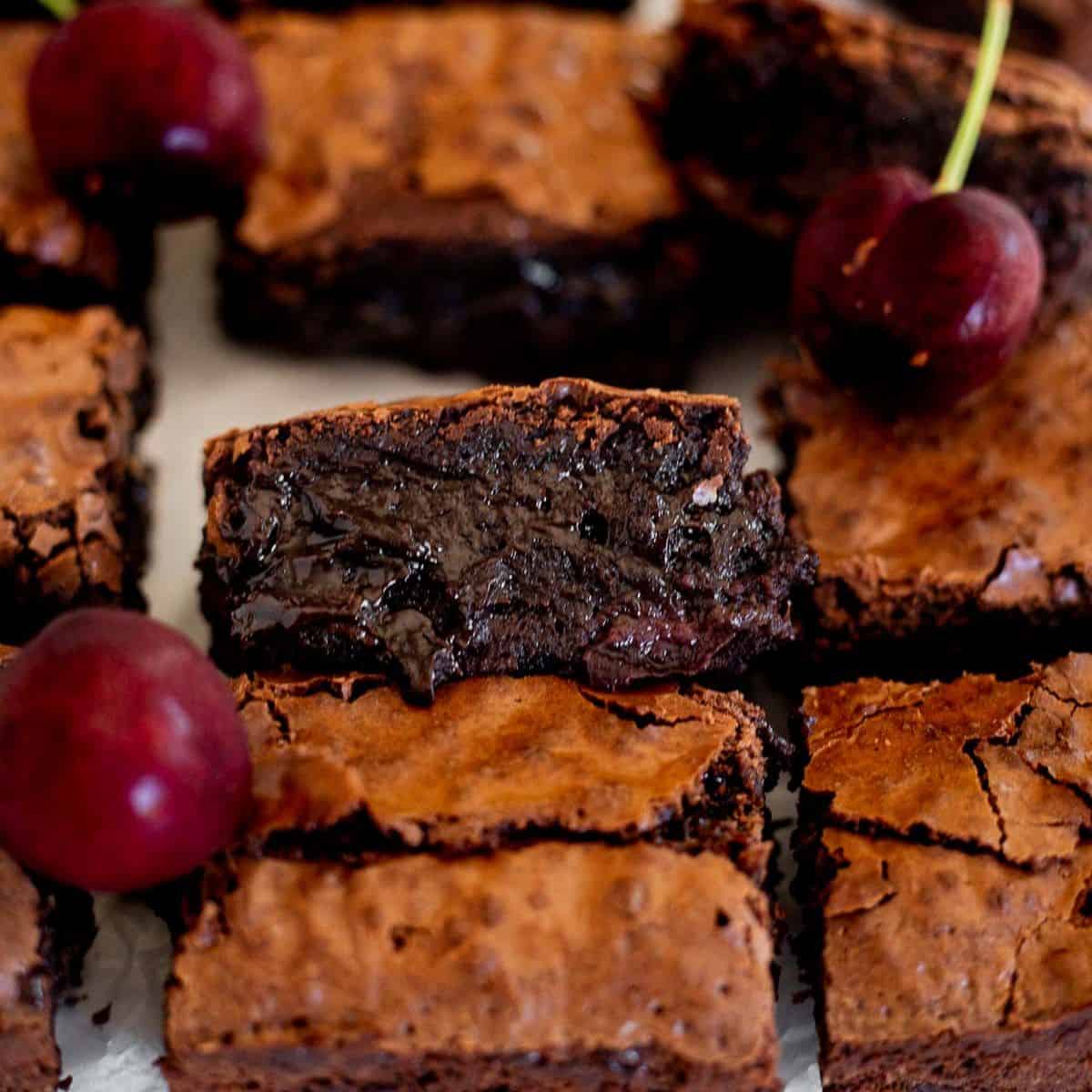 chocolate cherry brownies cut into squares on parchment paper.
