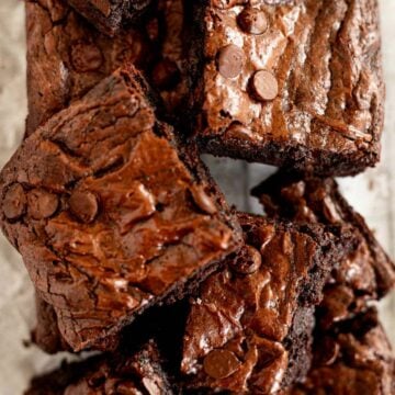 squares of small batch brownies piled on top of each other on parchment paper.