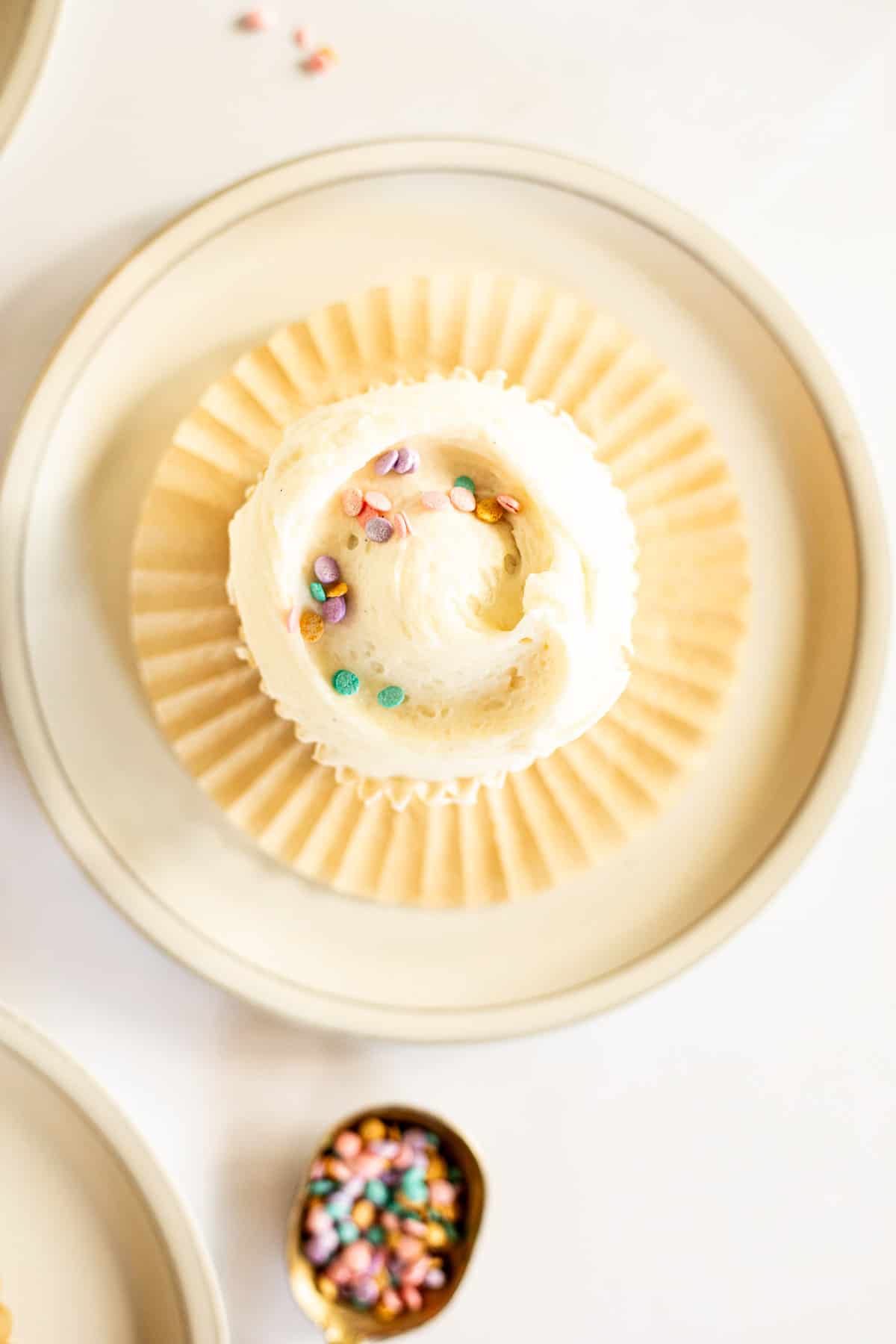 overhead photo of a vanilla bean cupcake topped with buttercream and sprinkles.