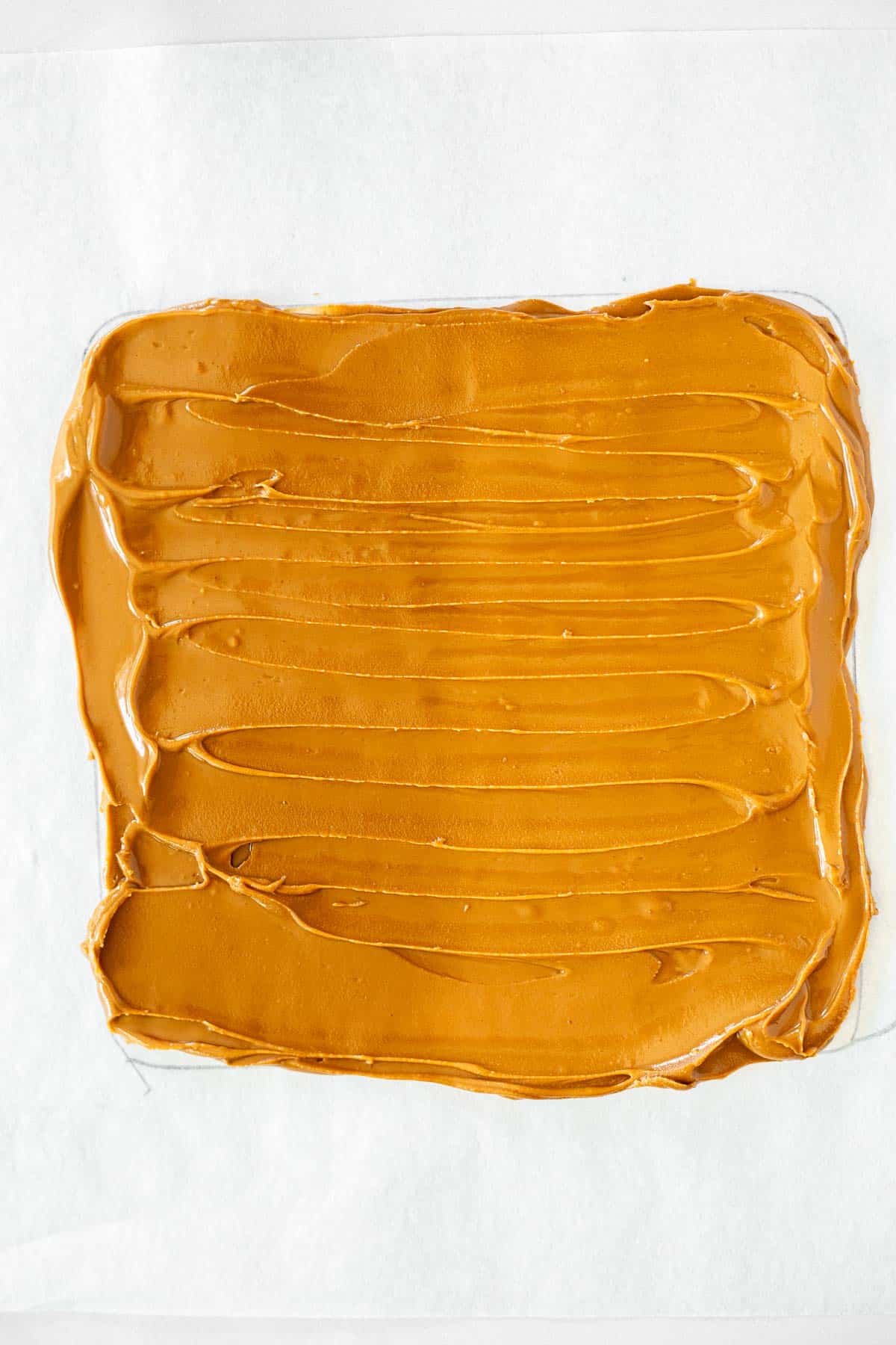 a layer of cookie butter spread into a square on parchment paper.