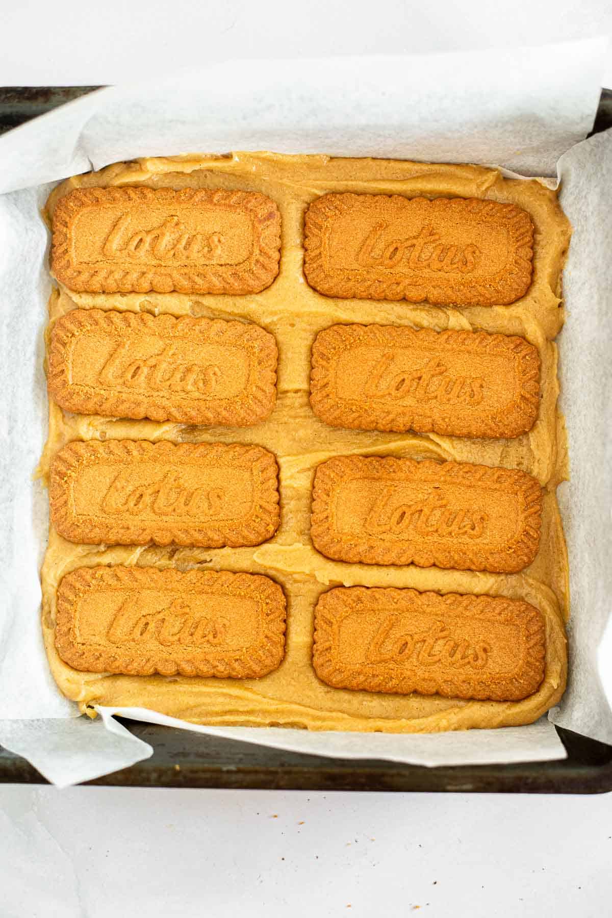 blondie batter with 2 rows of 4 Lotus biscuits on top.