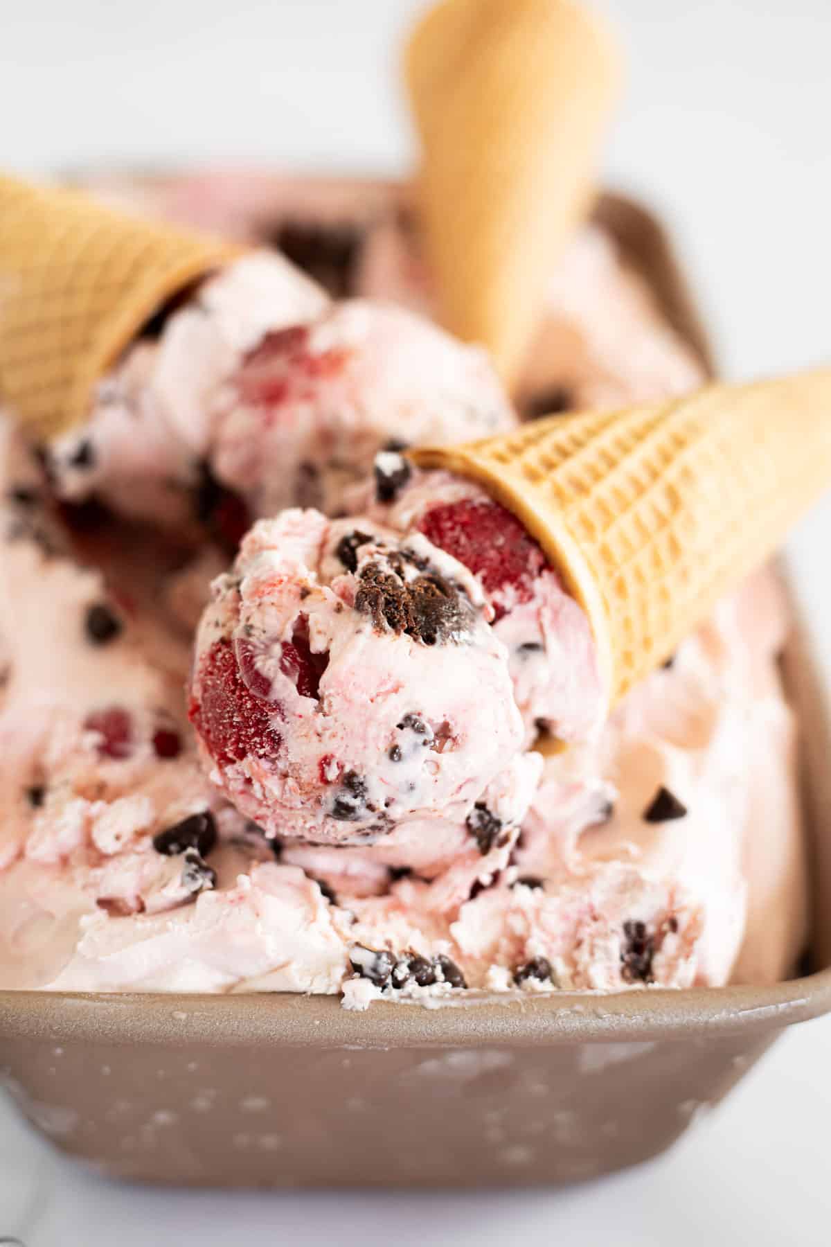 scoops of chocolate cherry ice cream in cones.