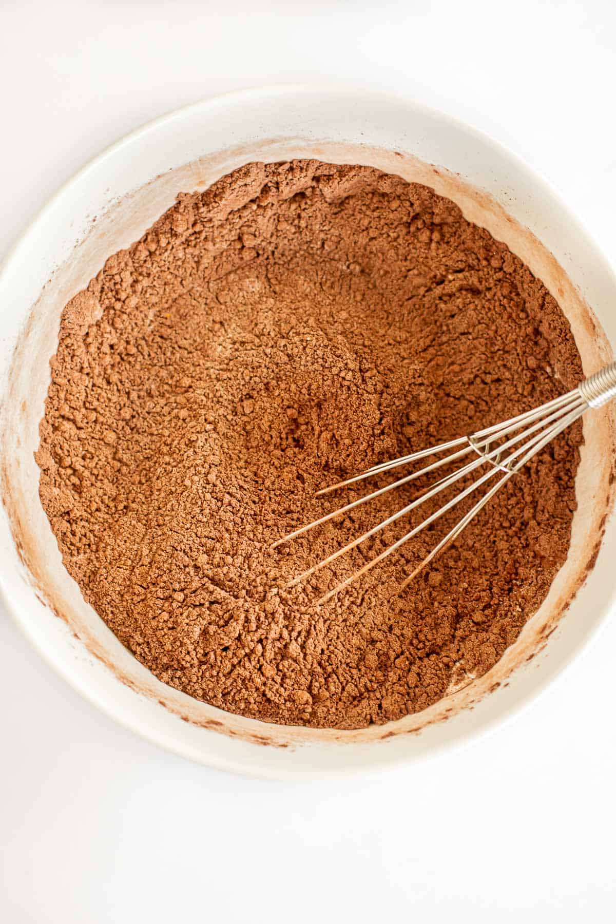 flour, cocoa powder, and sugar whisked together in a white bowl.