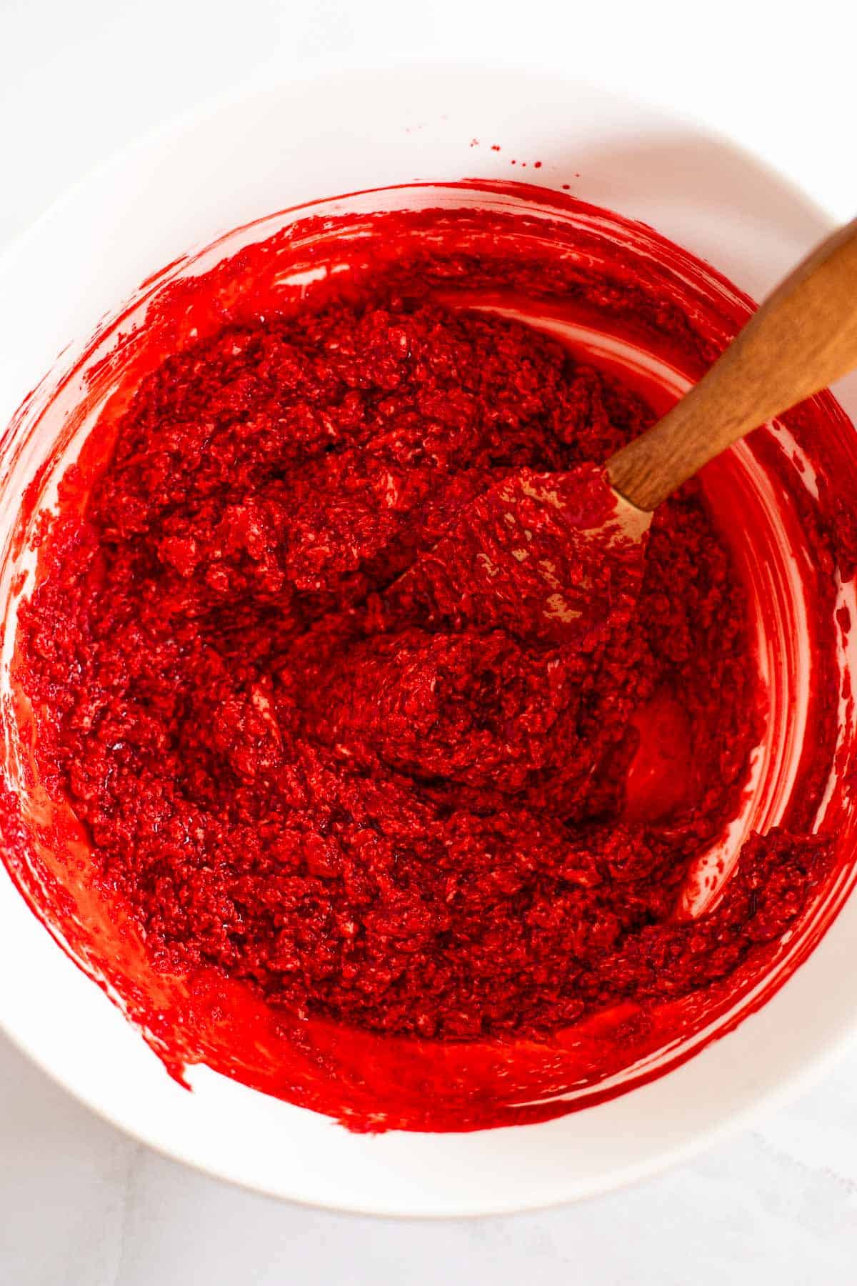 butter mixed with red food dye and sugar in a white bowl.