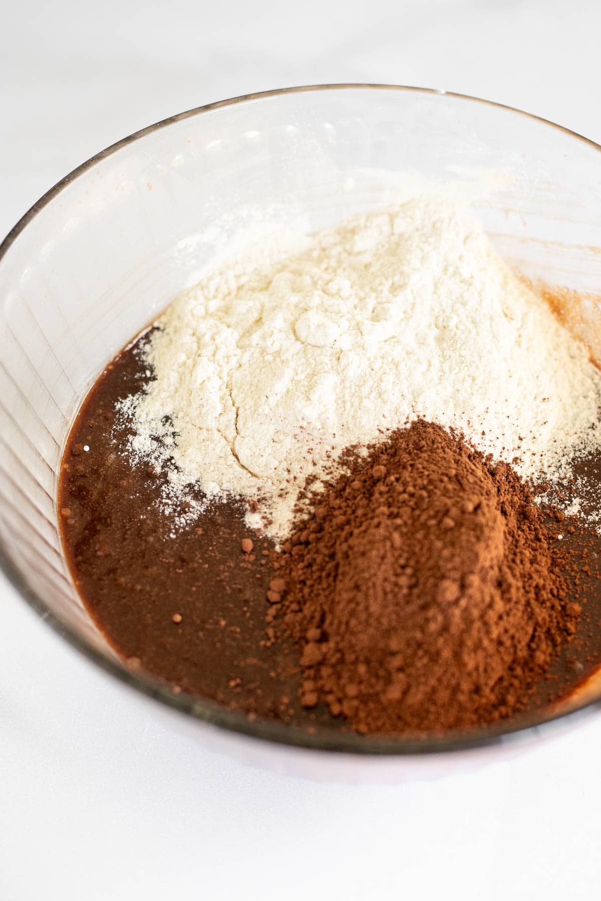 flour and cocoa powder in a glass bowl with melted chocolate.