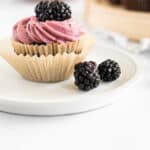 chocolate and blackberry cupcake on a white plate.