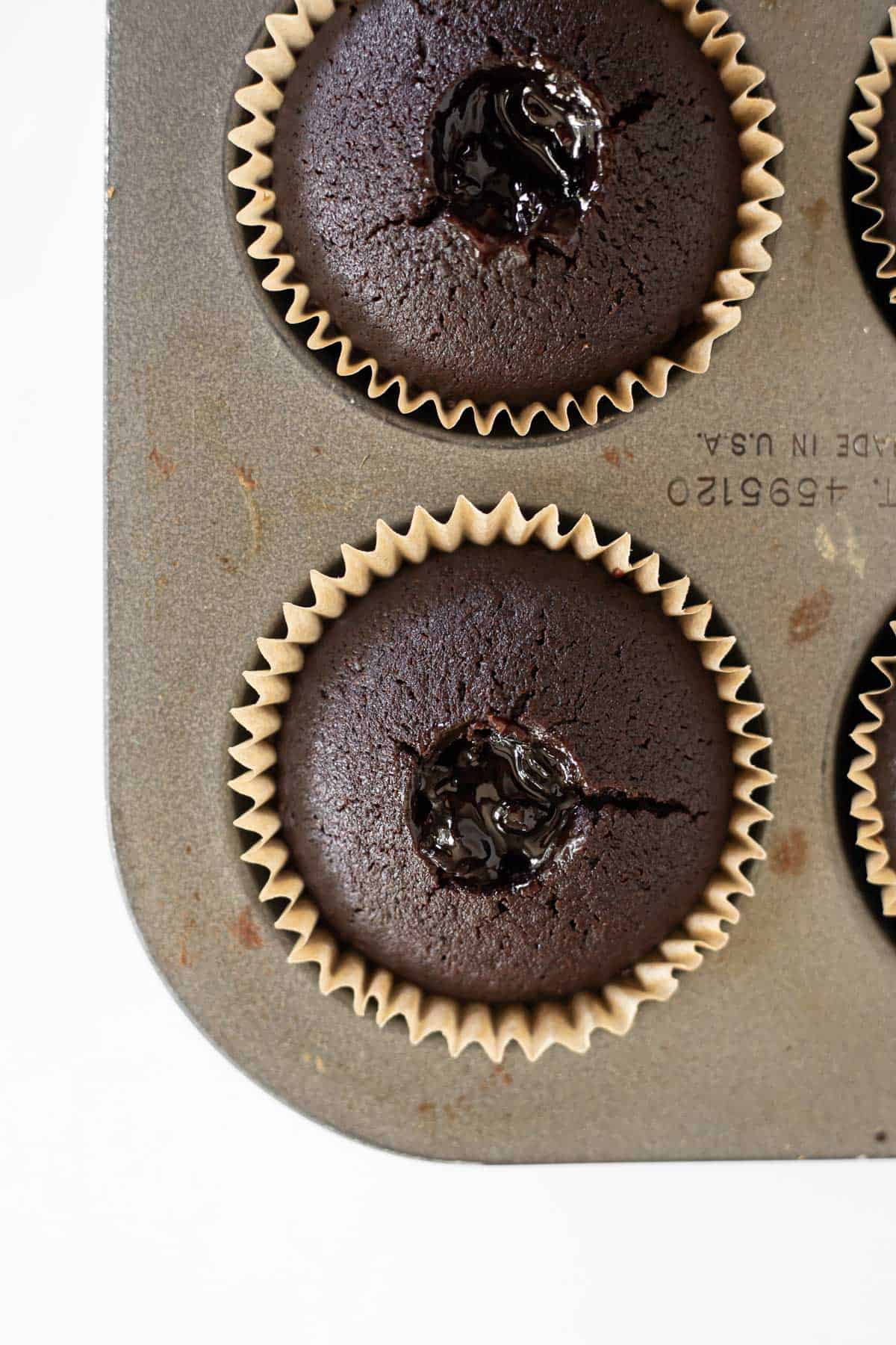 baked chocolate cupcakes cored and filled with blackberry jam.