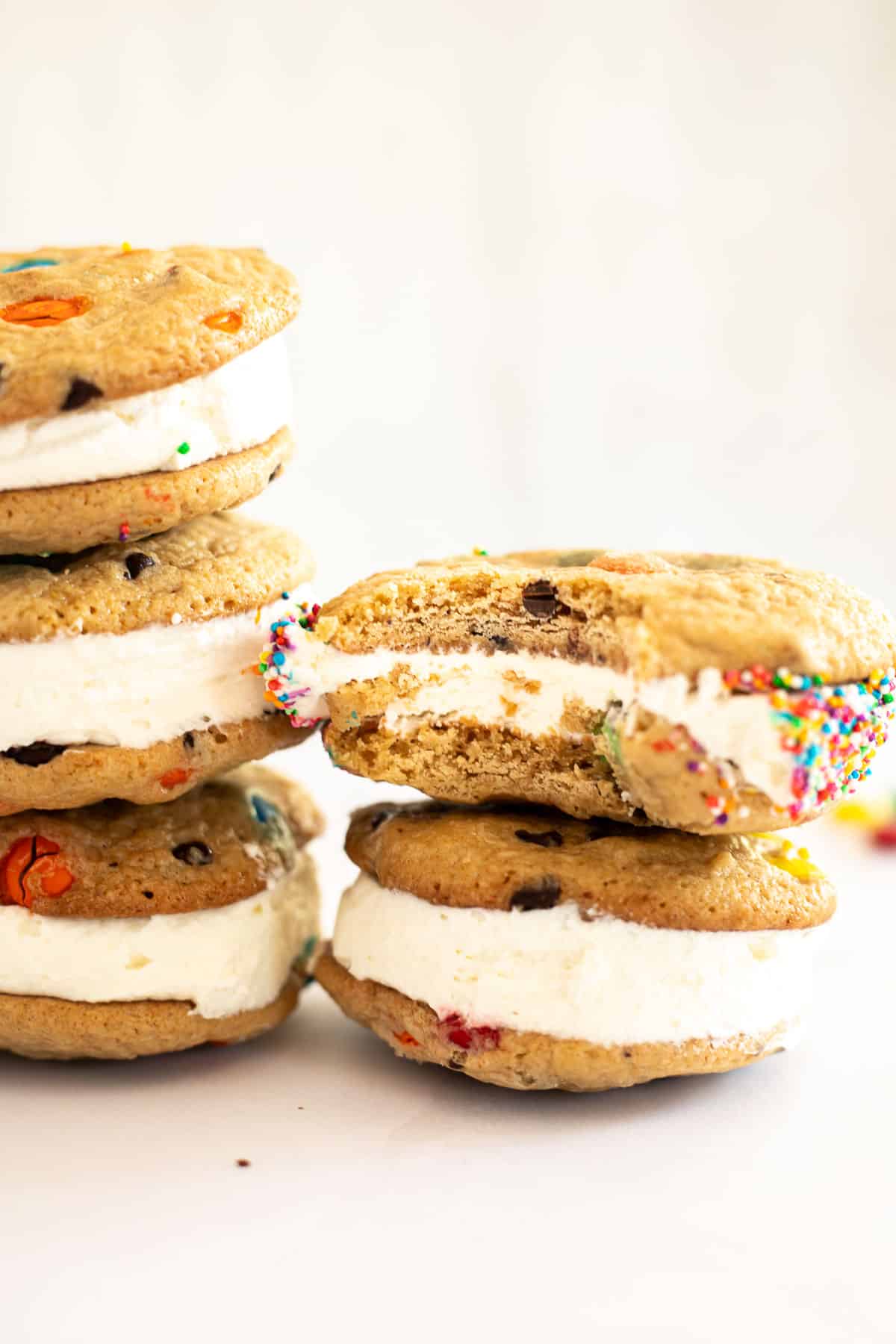 5 M&M ice cream sandwiches stacked with  a bite in one.