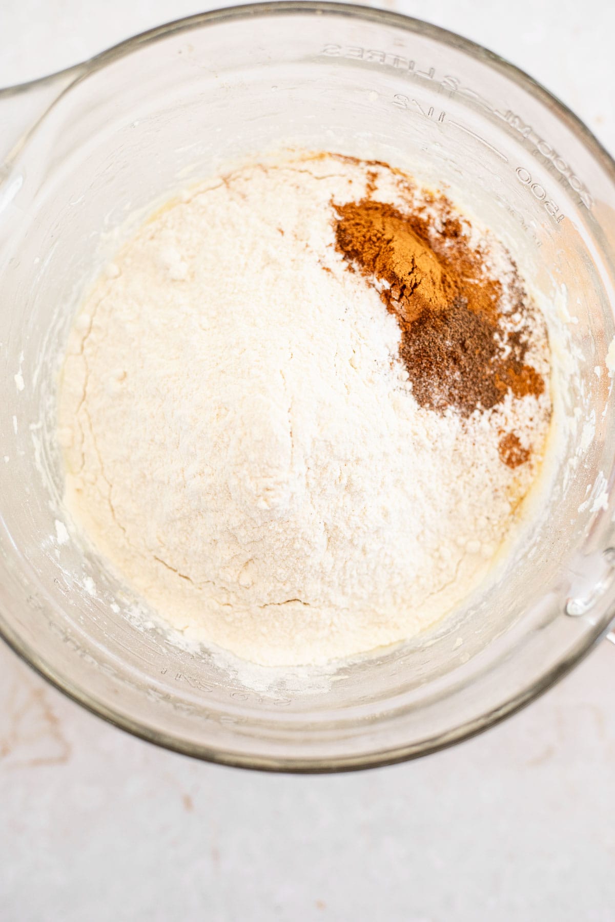 flour and cinnamon on top of cake batter in a glass bowl.