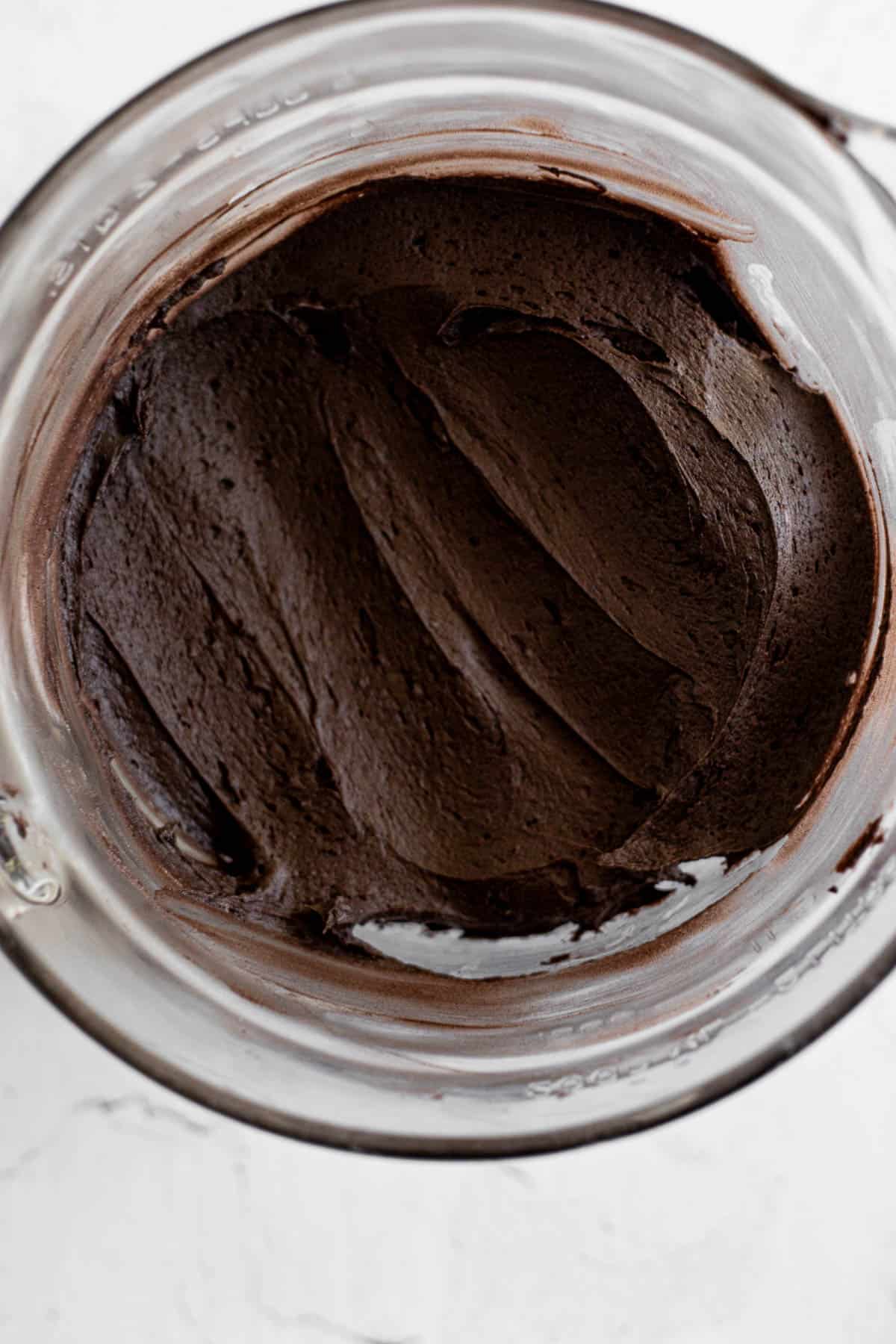 black cocoa buttercream frosting in a glass mixing bowl.