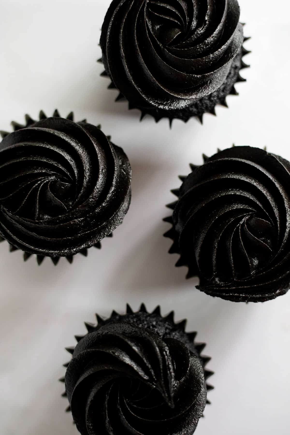 overhead photo of 4 black cocoa cupcakes topped with a black cocoa buttercream.