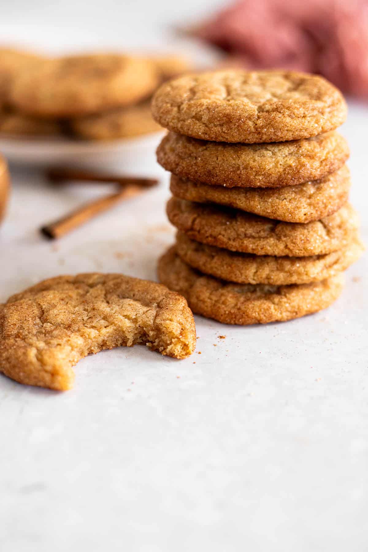 brown butter snickerdoodles stacked next to a cookie with a bite in it.