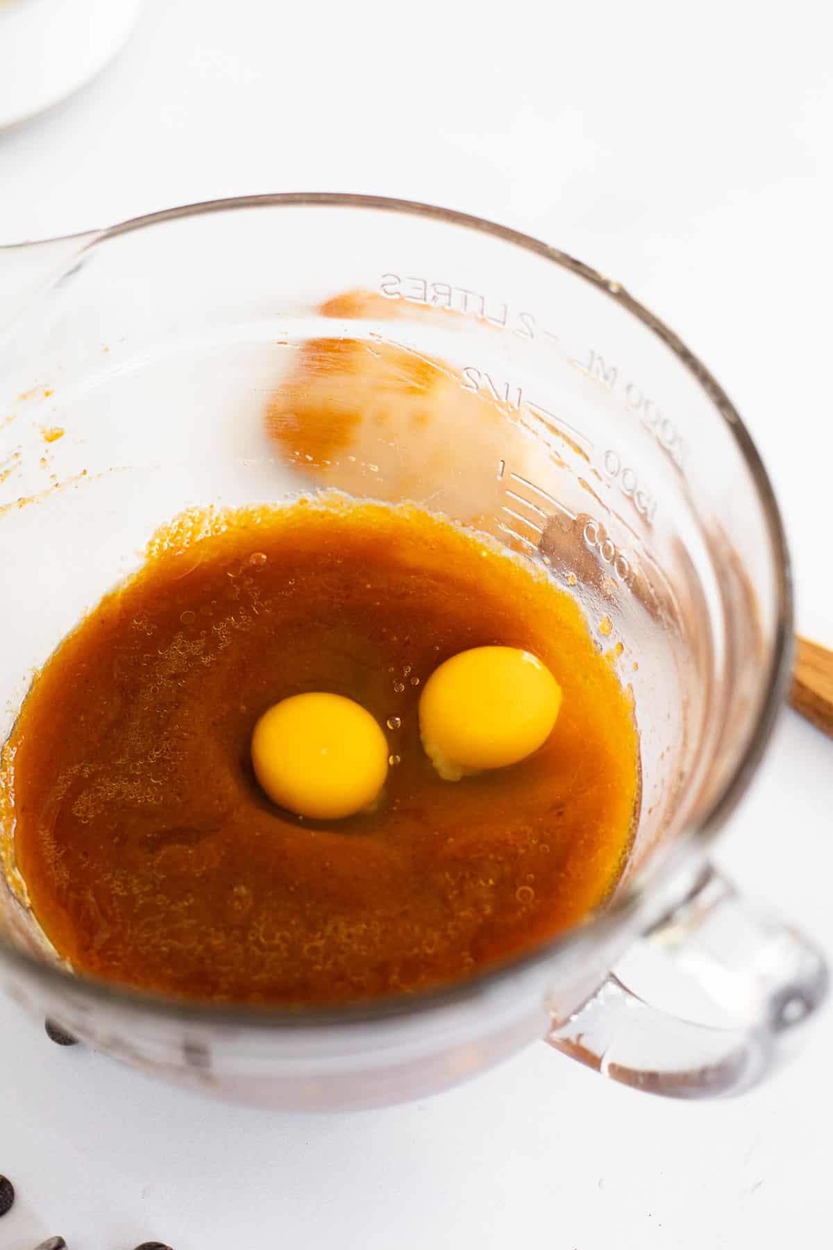 two eggs cracked into a glass bowl of pumpkin bread batter. 