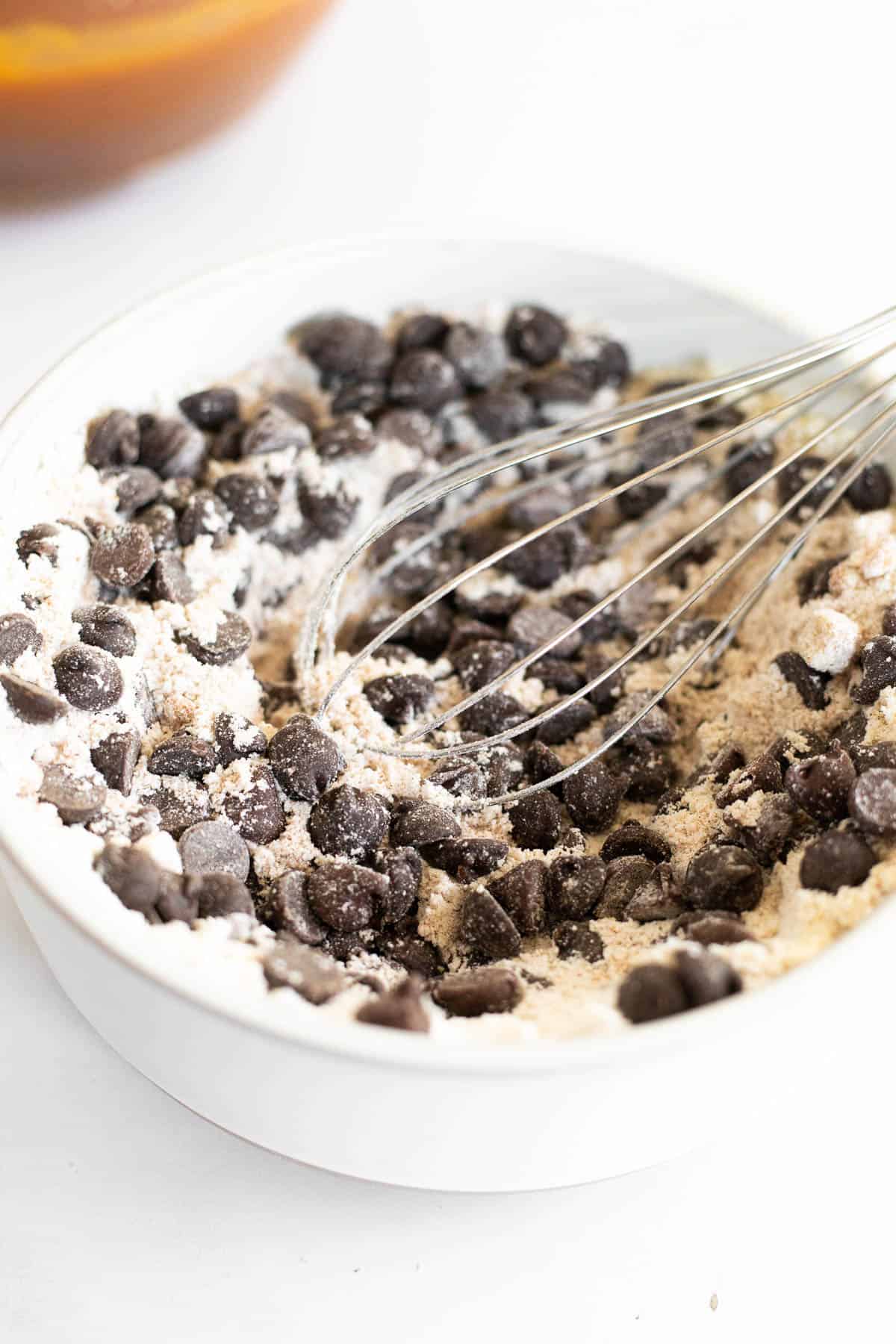 gluten free flour and chocolate chips whisked together in a mixing bowl.