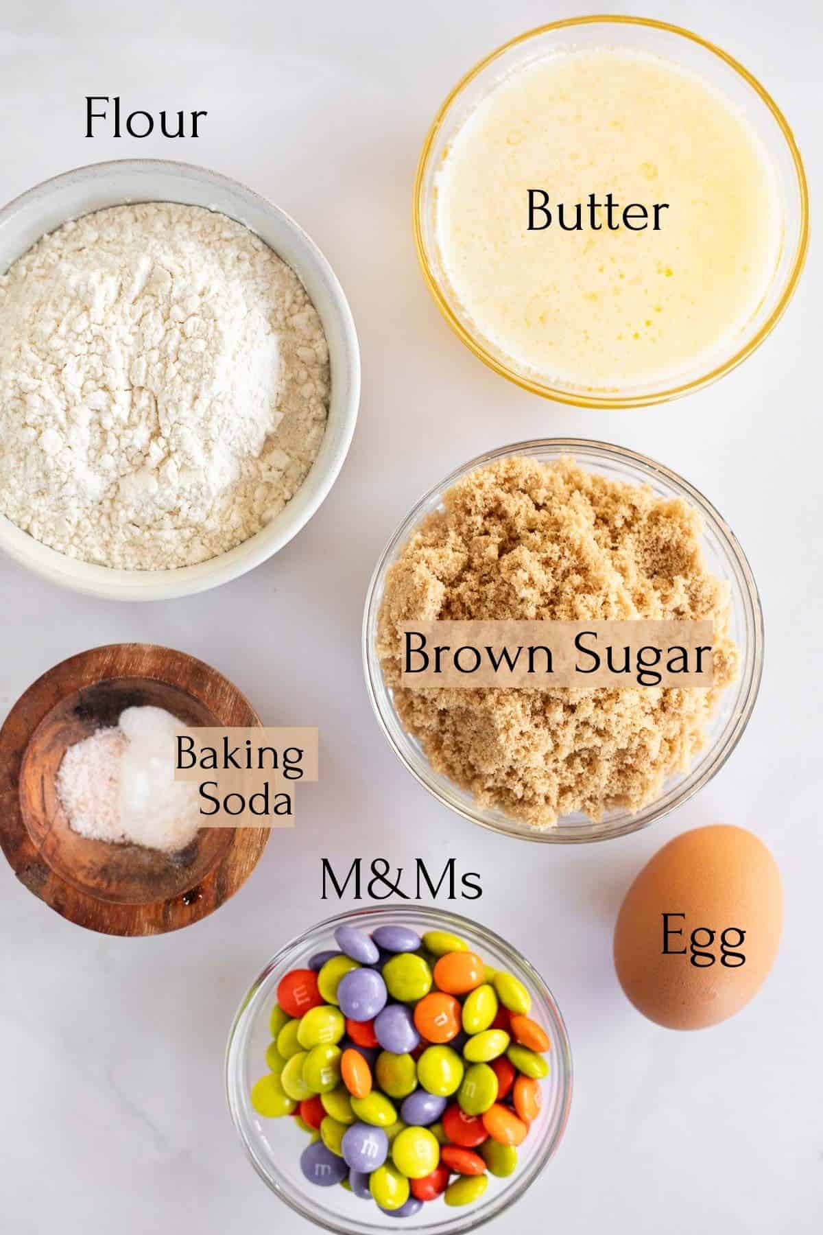 ingredients to make chewy M&M cookies labeled with black text.