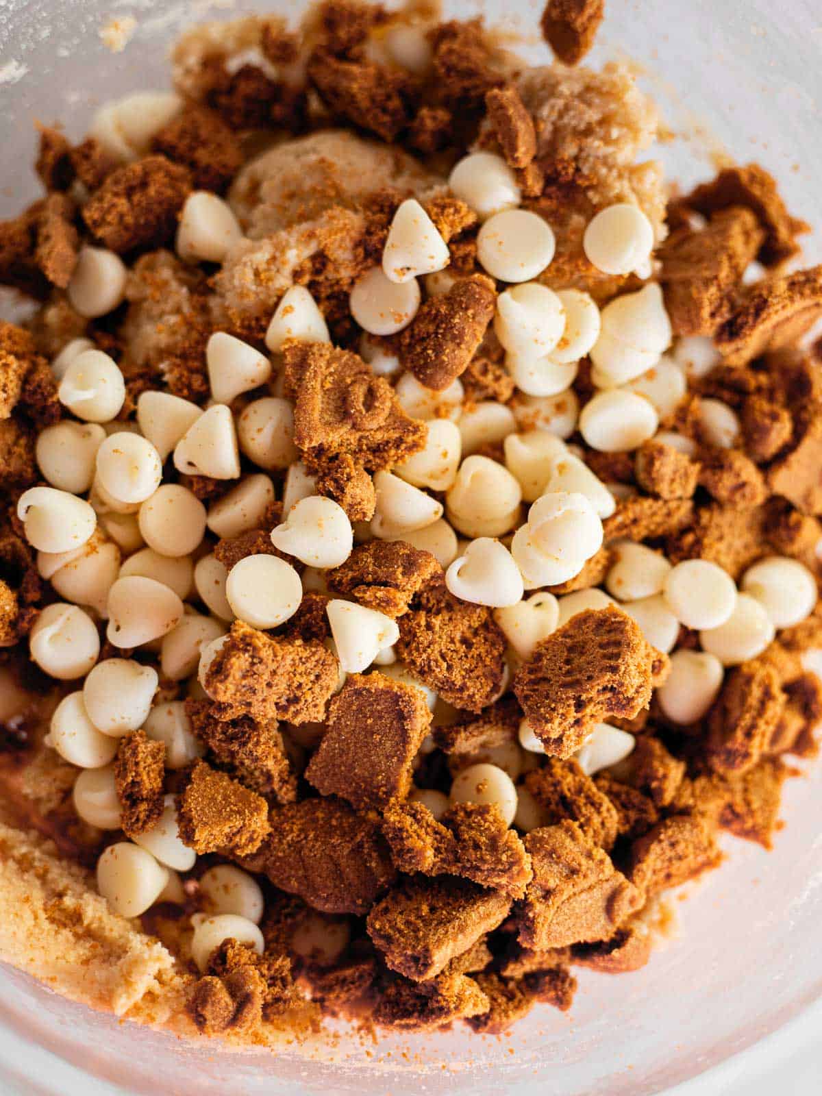 white chocolate chips and crushed biscoff biscuits in a bowl of cookie dough.